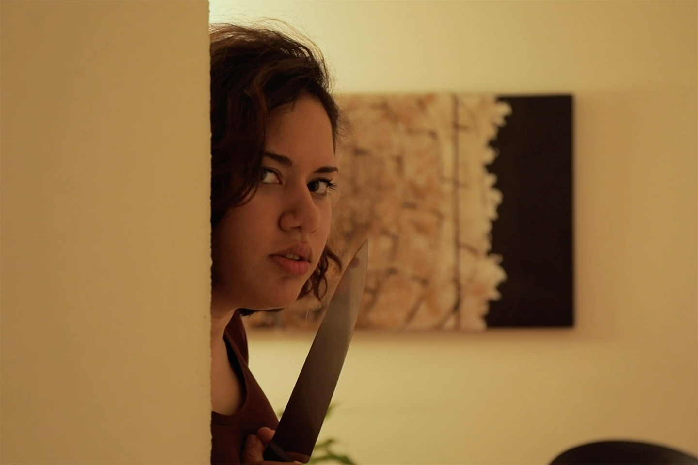 Femme munie d’un couteau cachée au coin d’un mur.